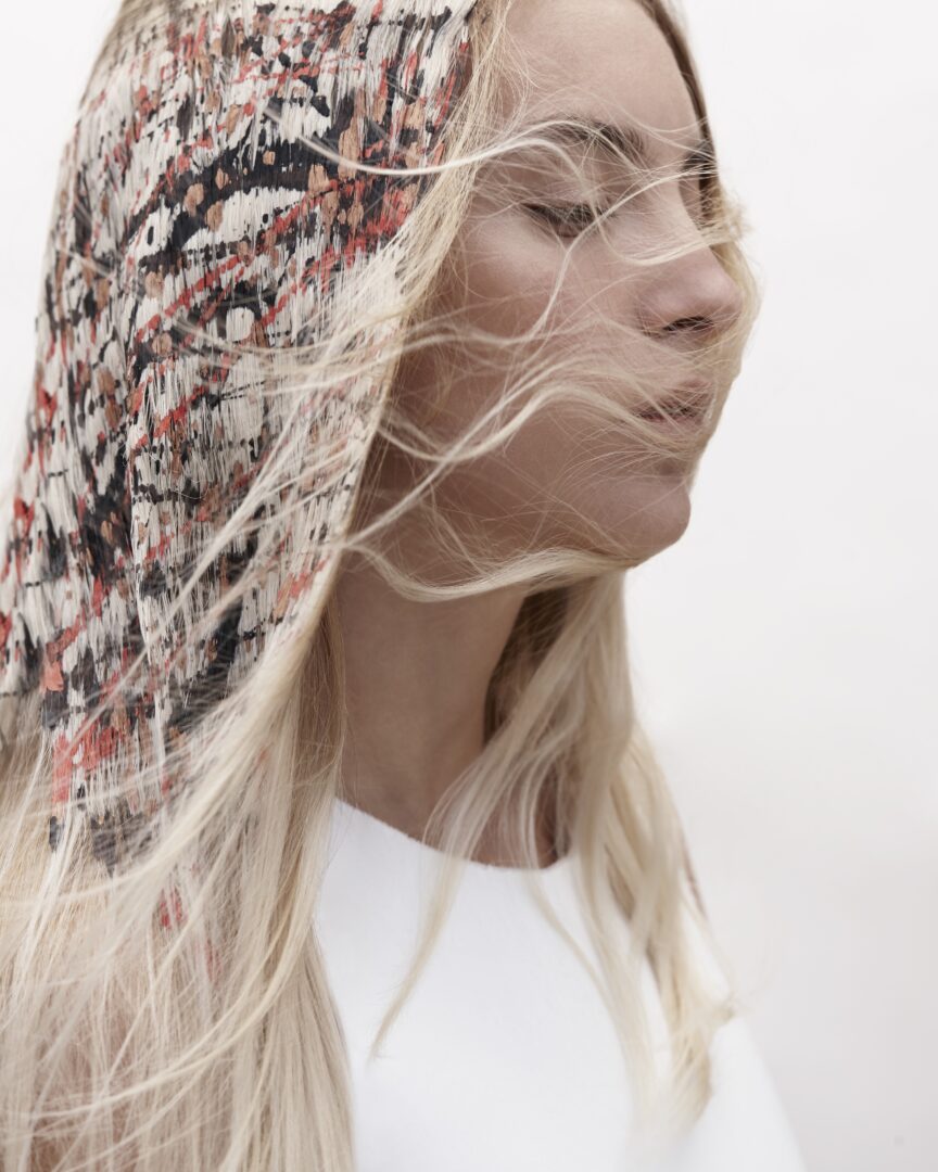 A blonde woman with long hair blowing in the wind.