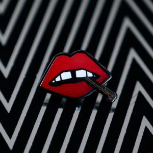 A black and white enamel pin with "Lips" enamel lapel pin by LH™ on it.