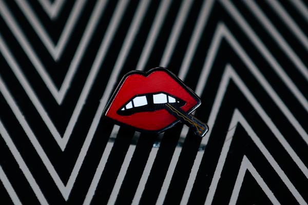 A black and white enamel pin with "Lips" enamel lapel pin by LH™ on it.